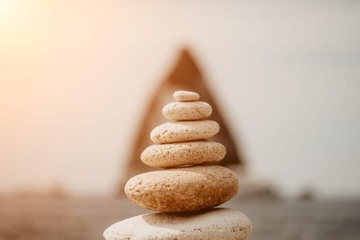 Pyramid stones on the seashore with warm sunset on the sea background. Happy holidays. Pebble beach, calm sea, travel destination. Concept of happy vacation on the sea, meditation, spa, calmness.