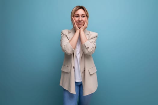 surprised blond young business woman in jacket on studio background.