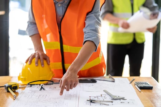 closed up engineer architect pointing to a building plan on a blueprint, engineer architect working with blueprints in office. High quality photo