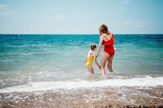 Happy loving family mother and daughter having fun together on the beach. Mum playing with her kid in holiday vacation next to the ocean - Family lifestyle and love concept.