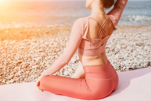 Middle aged well looking woman with black hair doing Pilates with the ring on the yoga mat near the sea on the pebble beach. Female fitness yoga concept. Healthy lifestyle, harmony and meditation.