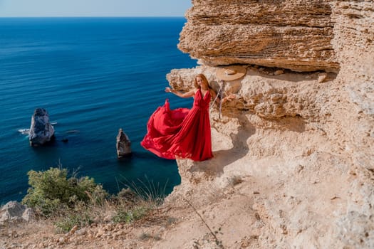 A woman in a red flying dress fluttering in the wind, against the backdrop of the sea