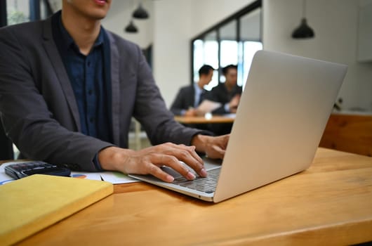 Cropped shot of male entrepreneur using laptop computer, working online sale marketing at modern workplace.