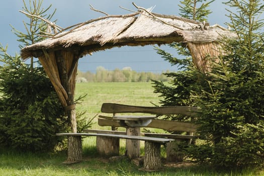 An old wooden gazebo for relaxing in the park. Equipped with wooden tables and benches.