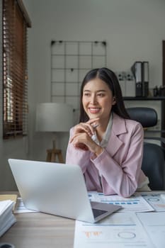 Asian businesswoman smile in office happy and cheerful using laptop and working.