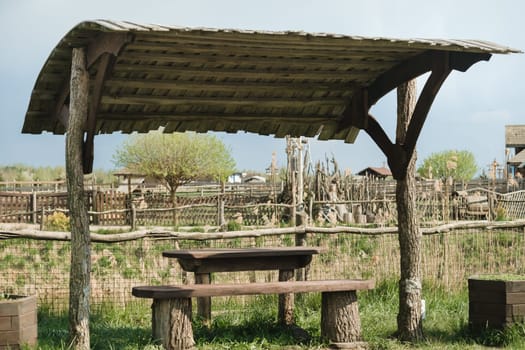 An old wooden gazebo for relaxing in the park. Equipped with wooden tables and benches.