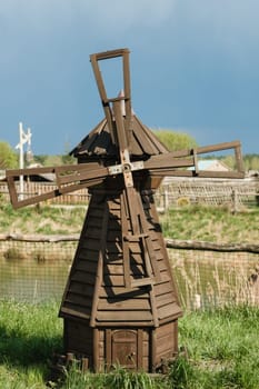 Decorative wooden mill standing outside in summer.