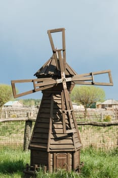 Decorative wooden mill standing outside in summer.