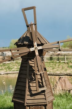 Decorative wooden mill standing outside in summer.