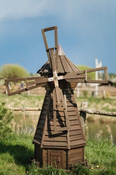 Decorative wooden mill standing outside in summer.