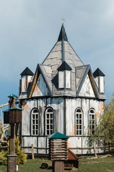 A small white house with a pointed roof stands on the street.