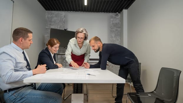 The female boss evaluates the work of subordinates. Designers engineers at a meeting