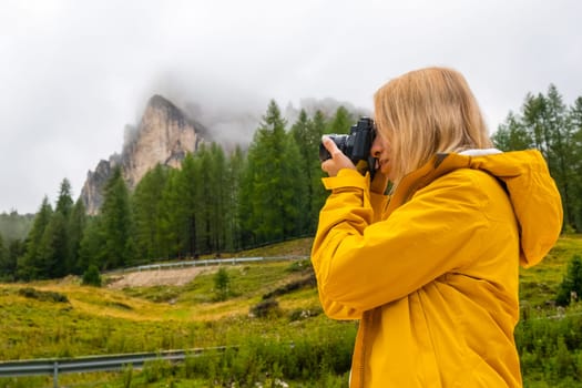 A blonde tourist capturing photographs of the picturesque meadows in the stunning Alpine mountain range.