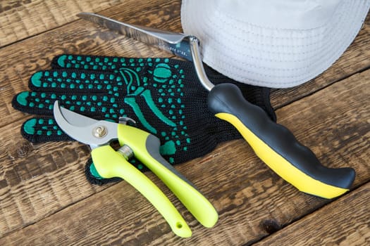Garden gloves, pruner, trowel and hat on wooden board. Garden tools and equipment