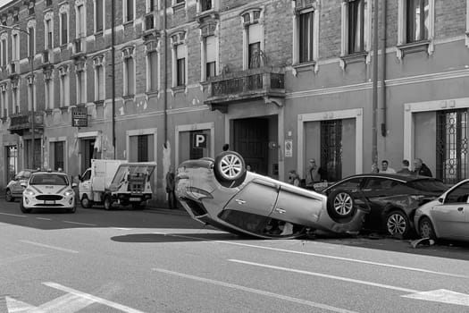 Cremona, Italy - 18th April 2023 just rolled over crashed car after an accident, police officer helping with traffic