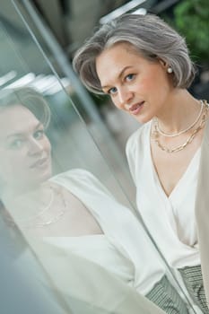 Portrait of a beautiful gray-haired caucasian woman at the glass door