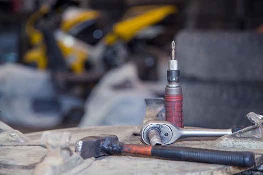 Screwdriver, wrench and hammer on a metal workbench in a workshop. In the garage are tools for repairing broken vehicle parts. Small business concept, car repair and maintenance service.