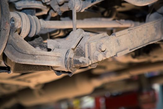 Worn and rusty rear suspension arms, rods and bushings. In the garage, a person changes the failed parts on the vehicle. Small business concept, car repair and maintenance service.