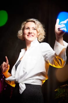 An elegant blonde girl in white blouse in a room decorated for Christmas or new year with a background, tinsel and light garlands