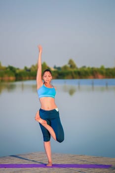 girl doing yoga exercises on the river bank at sunset