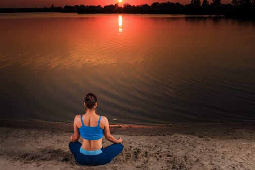 yoga at sunset on the beach. woman doing yoga, performing asanas and enjoying life on the river