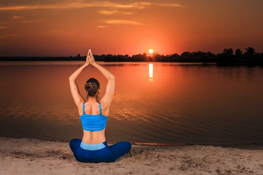 yoga at sunset on the beach. woman doing yoga, performing asanas and enjoying life on the river