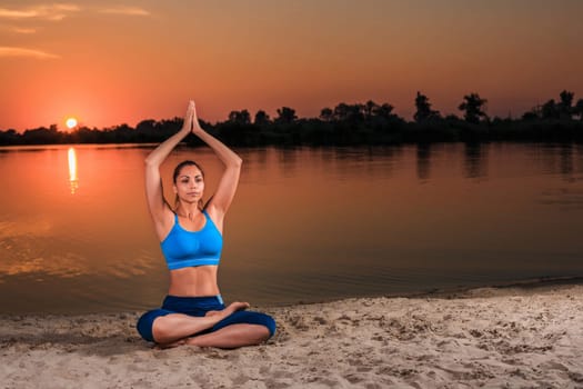 yoga at sunset on the beach. woman doing yoga, performing asanas and enjoying life on the river