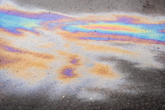 Colored texture of oil products on the asphalt in the rain. Bold multicolored spots on the asphalt