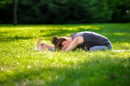 Young fitness woman meditation in a city park.Yoga at sunset in the park. Girl is practicing yoga. Fitness training outdoors. Attractive fitness woman. Workout outdoors. Healthy lifestyle