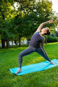Young fitness woman meditation in a city park.Yoga at sunset in the park. Girl is practicing yoga. Fitness training outdoors. Attractive fitness woman. Workout outdoors. Healthy lifestyle