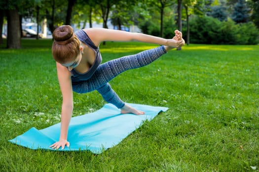 Young fitness woman meditation in a city park.Yoga at sunset in the park. Girl is practicing yoga. Fitness training outdoors. Attractive fitness woman. Workout outdoors. Healthy lifestyle