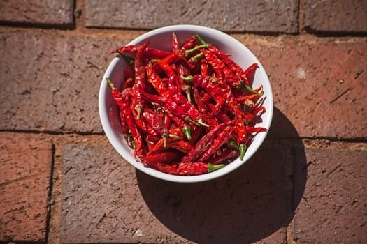 A bowl of sun dried Red Hot Chili Peppers on paving