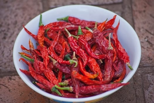 A bowl of sun-dried Red-Hot Chili Peppers on paving