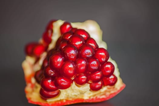 Ripe Pomegranate seeds in the fruit body on a dark blurred background