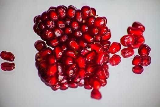 Ripe Pomegranate seeds in the fruit body on a white blurred background