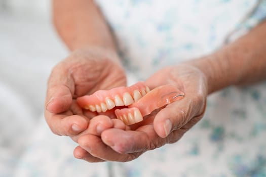 Asian elderly woman patient holding to use denture, healthy strong medical concept.