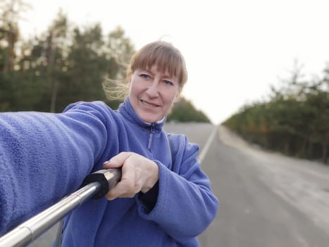 girl woman takes a selfie on cell phone against the background of a road outside on a natural landscape. Happy Female tourist on a trip and travel