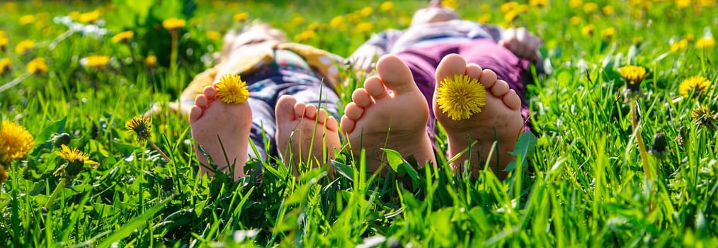 Child feet on the grass in the spring dandelions garden. Selective focus. nature.