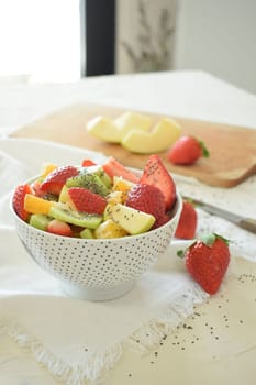 Bowl of fresh fruit salad, kiwi, apples, oranges.
