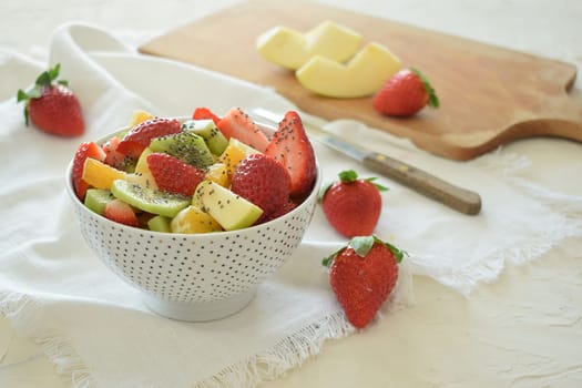 Bowl of fresh fruit salad, kiwi, apples, oranges.