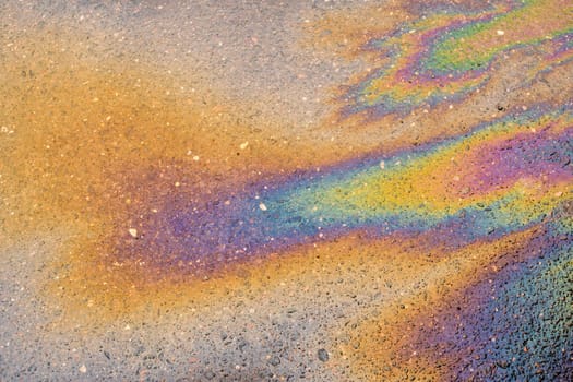 Spilled oil on the asphalt road background.