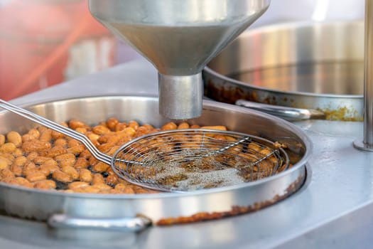 The process of cooking lokma, the cook cooks lokma in a deep fryer. Industrial production of a popular Middle Eastern dessert made from deep-fried dough balls. Little donuts