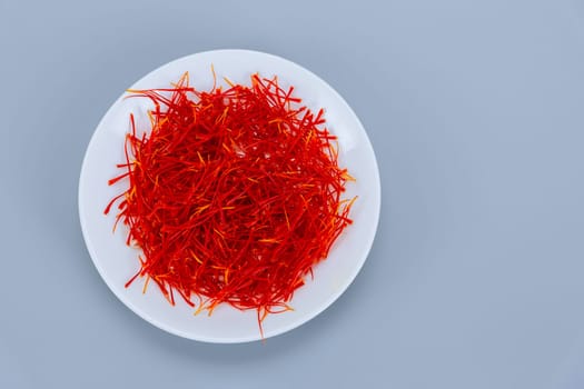 Saffron stamens in a white plate on a white background, place for text. drying of saffron stamens, saffron spice.