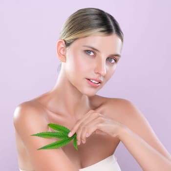 Alluring beautiful woman model portrait holding green leaf as concept for cannabis skincare cosmetic product for perfect skin freshness treatment in isolated pink background.