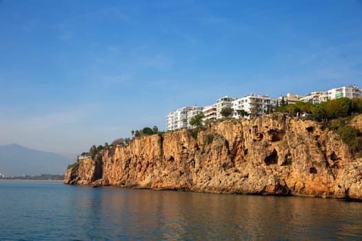 Roacks with buildings on a sea coast with horizon on a background. Antalya, Turkiye.