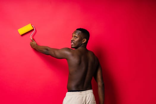 African-American painter on a red studio background topless