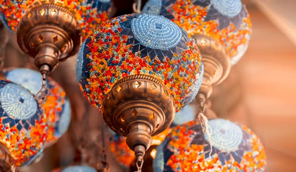 Middle Eastern lambas of different colors and sizes are hanging in the bazaar. Bright traditional Arabic and Turkish lanterns made of metal and glass, inlaid with mosaic details of different colors.