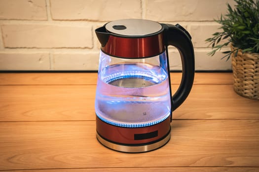 a new red modern boiling glass electric kettle close-up with bubbling water and blue neon lighting.