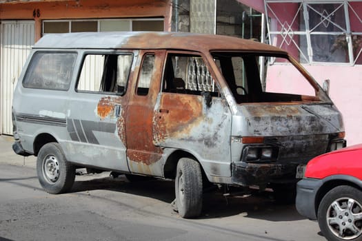 Mexico City, Mexico, October 2019. Burned out car by the side of the road. Nobody in the vehicle.