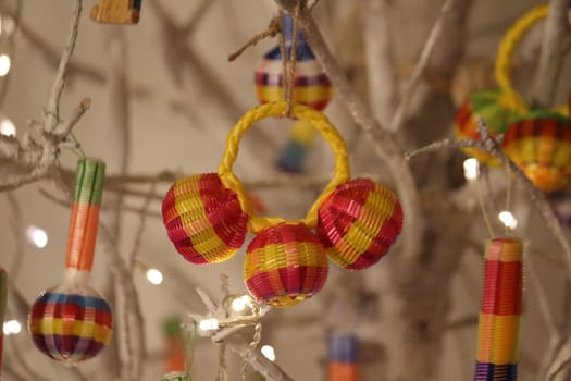 Decorative colorful reed Christmas ornament, hanging in a white brenched tree.